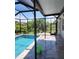 Screened-in pool area with a sparkling pool, patio, and tropical foliage creating a serene outdoor space at 15301 Chinook Way, Port Charlotte, FL 33981