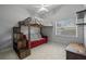 Bright bedroom featuring a bed lofted over a red couch, creating a cozy space at 28707 Raleigh Pl, Wesley Chapel, FL 33545