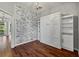 Stylish bedroom with a Murphy bed, hardwood floors, a brick accent wall, and built-in shelving for storage at 28707 Raleigh Pl, Wesley Chapel, FL 33545