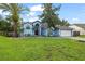 Beautiful single-story home featuring a well-manicured lawn, landscaping, a two-car garage, and a blue exterior at 28707 Raleigh Pl, Wesley Chapel, FL 33545