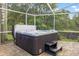 Inviting hot tub with steps inside a screened patio overlooking a lush yard at 28707 Raleigh Pl, Wesley Chapel, FL 33545