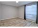 Bedroom featuring wood-look floors, gray walls, and large window with shades at 9516 Woodborough Ct, Tampa, FL 33615