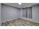 This is an empty bedroom with gray walls, light-colored wood floors, and a window with gray curtains at 9516 Woodborough Ct, Tampa, FL 33615