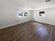 Bright bedroom featuring wood floors, a ceiling fan, and two windows at 5511 Drinkard Dr, New Port Richey, FL 34653