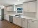 Kitchen features stainless dishwasher, sink, and a stone countertop and white cabinets at 5511 Drinkard Dr, New Port Richey, FL 34653