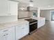 Bright kitchen with stainless steel appliances, stone countertops, white cabinets and views to open living area at 5511 Drinkard Dr, New Port Richey, FL 34653