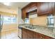 Well-lit kitchen featuring granite countertops, tile floors, and stainless-steel dishwasher at 2002 Culpepper Dr, Brandon, FL 33511