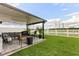Covered patio area with outdoor seating, landscaping, and a white fence enclosing a lush green yard at 4704 Wild Senna Blvd, Tampa, FL 33619