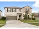 Two-story home featuring neutral stucco, dark shutters, a two-car garage, and landscaped front yard at 4704 Wild Senna Blvd, Tampa, FL 33619