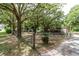 Backyard featuring mature trees, lawn, and home with gate at 26627 Brahma Dr, Wesley Chapel, FL 33544