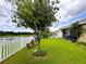 Picture of the home's backyard, highlighting a green lawn, waterfront, mature shade tree, and outdoor seating at 11124 Leland Groves Dr, Riverview, FL 33579