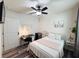 Well-lit bedroom with wood-look flooring, a ceiling fan, a white metal bed frame, and a cozy desk area at 11124 Leland Groves Dr, Riverview, FL 33579