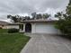 Front exterior featuring a concrete driveway, a two-car garage, and mature trees around the house at 13382 Drummond Ave, Port Charlotte, FL 33953