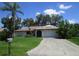 Single-story home with a palm tree and a driveway leading to an attached two-car garage at 13382 Drummond Ave, Port Charlotte, FL 33953