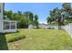 Large, grassy backyard enclosed by a white fence and lush trees at 707 63Rd S Ave, St Petersburg, FL 33705