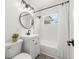 Bright bathroom featuring a white vanity, a round mirror, a shower-tub combo, and modern fixtures and lighting at 707 63Rd S Ave, St Petersburg, FL 33705