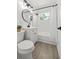 Bright bathroom featuring a white vanity, a round mirror, a shower-tub combo, and modern fixtures and lighting at 707 63Rd S Ave, St Petersburg, FL 33705