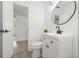 Stylish bathroom with a floating vanity, a modern round mirror, updated fixtures, and wood-look flooring at 707 63Rd S Ave, St Petersburg, FL 33705