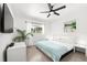 Bright bedroom with light wood floors, a ceiling fan, two windows, and a comfortable bed at 707 63Rd S Ave, St Petersburg, FL 33705
