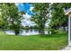Backyard featuring a serene lake view, mature trees, and lush green lawn at 7728 Balharbour Dr, New Port Richey, FL 34653