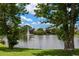 Lush backyard featuring a beautiful lake view with water fountain and mature trees at 7728 Balharbour Dr, New Port Richey, FL 34653