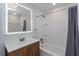 Modern bathroom featuring an illuminated mirror, wood vanity, and a shower-tub combination for convenience at 7728 Balharbour Dr, New Port Richey, FL 34653