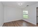 Minimalist bedroom with hardwood floors, a bright window, and a clean, serene aesthetic for relaxation at 7728 Balharbour Dr, New Port Richey, FL 34653