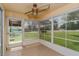 Enclosed sunroom featuring a ceiling fan, tile floor, and multiple windows overlooking the green lawn at 7728 Balharbour Dr, New Port Richey, FL 34653