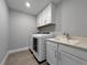 Laundry room equipped with modern washer/dryer units, white cabinetry, and a sink at 6256 Baywood Ct, Bradenton, FL 34211