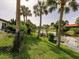 Manicured lawn slopes to a pond with palm trees and lush landscaping framing the yard at 1244 E Corktree Cir, Port Charlotte, FL 33952