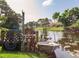 Wooden dock with a small boat on the pond, featuring lush landscaping and sunny skies at 1244 E Corktree Cir, Port Charlotte, FL 33952