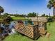Wooden dock and small fishing boat next to a grassy lawn and pond in a sunny, landscaped yard at 1244 E Corktree Cir, Port Charlotte, FL 33952