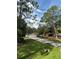 Single-story home with a long driveway and lush green lawn lined by mature trees at 9504 W Cluster Ave, Tampa, FL 33615