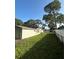 Back exterior view with well-maintained lawn, perimeter fence and mature trees, offering privacy and space at 9504 W Cluster Ave, Tampa, FL 33615