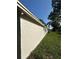 Side view of home showing textured stucco exterior and well-kept lawn, blending with the natural surroundings at 9504 W Cluster Ave, Tampa, FL 33615