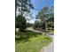 Well-manicured front yard showcasing lush grass and mature trees, leading to a charming home at 9504 W Cluster Ave, Tampa, FL 33615