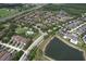 Wide aerial shot of a neighborhood with a lush park, pool, and lake, surrounded by beautiful homes and greenery at 12990 Burns Dr, Odessa, FL 33556