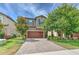 Charming two-story home featuring a brick driveway and a well-manicured front yard with mature trees at 12990 Burns Dr, Odessa, FL 33556