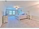 Spacious primary bedroom with a ceiling fan, two windows and seating area; well-lit with neutral decor at 12990 Burns Dr, Odessa, FL 33556
