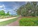 Scenic walking path meandering through lush landscaping and mature trees with a lake view at 12990 Burns Dr, Odessa, FL 33556