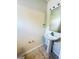 Modest bathroom with a pedestal sink, decorative mirror, tiled floors, and neutral-colored walls at 4605 Ashburn Square Dr, Tampa, FL 33610