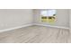 Bright bedroom with light gray walls, wood-look floors, baseboard trim, and a large window overlooking the yard at 4798 Jody Ave, North Port, FL 34288