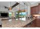 Close-up of a large kitchen island with granite countertop, bar seating, and stainless steel appliances at 7315 Bianco Duck Ct, Sarasota, FL 34240
