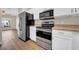 Kitchen featuring white cabinets, stainless steel appliances, and hardwood floors at 5857 Fishhawk Ridge Dr, Lithia, FL 33547