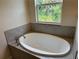 Oval-shaped bathtub with grey tile surround and window at 4619 Chamrade Rd, North Port, FL 34288