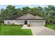 One-story house with gray siding, dark roof, two-car garage, and landscaped lawn at 16041 Scaup Duck Ave, Weeki Wachee, FL 34614