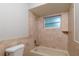 Clean bathroom with tub, tiled walls, and single window at 15123 Copeland Way, Spring Hill, FL 34604