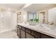 Modern bathroom with double sinks, dark wood vanity, and a walk-in shower at 30942 Wild Juniper Ct, Brooksville, FL 34602