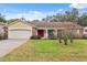 Ranch-style house featuring a yellow exterior, red front door, and green lawn at 8550 Berkley Dr, Hudson, FL 34667