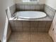 Elegant soaking tub with tiled surround and a large window at 7724 Swiss Ave, North Port, FL 34291